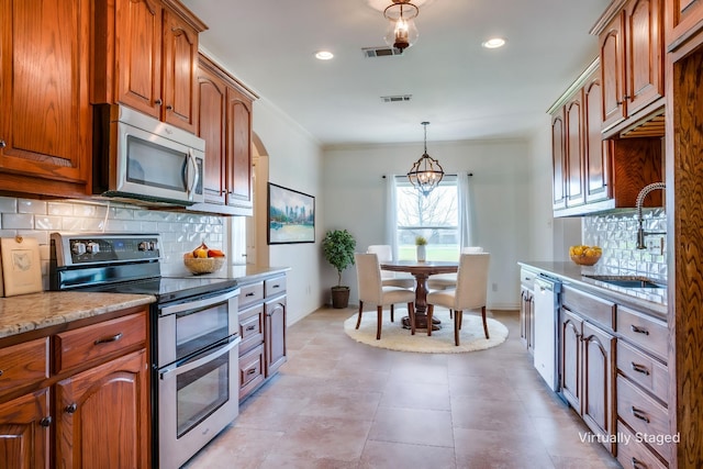 kitchen with light stone counters, decorative backsplash, a sink, visible vents, and stainless steel appliances