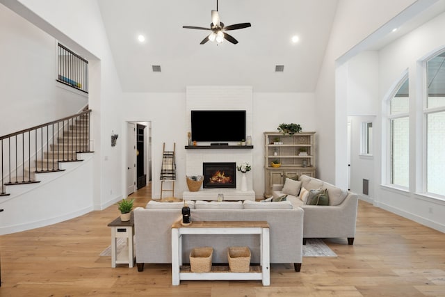 2720 Whirlaway Ct, Celina, TX 75009 - living room with high vaulted ceiling, ceiling fan, a brick fireplace, light wood-style flooring, and stairway
