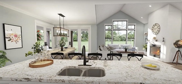 kitchen featuring wood finished floors, a sink, open floor plan, a glass covered fireplace, and light stone countertops