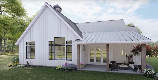 back of property with french doors, a standing seam roof, a chimney, metal roof, and a yard