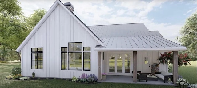 back of property with board and batten siding, a standing seam roof, french doors, and metal roof