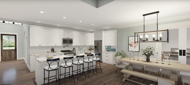 kitchen with white cabinets, a breakfast bar, backsplash, appliances with stainless steel finishes, and dark wood-style floors