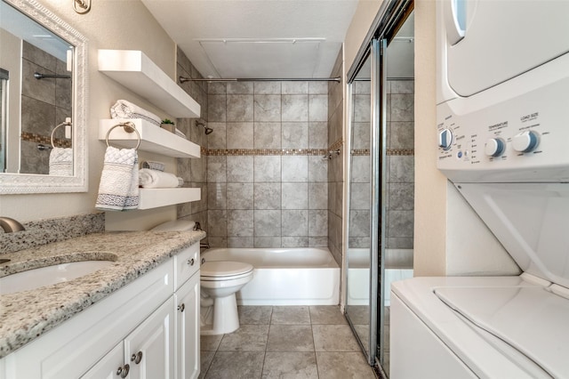 bathroom featuring vanity, shower / washtub combination, tile patterned floors, toilet, and stacked washer / drying machine