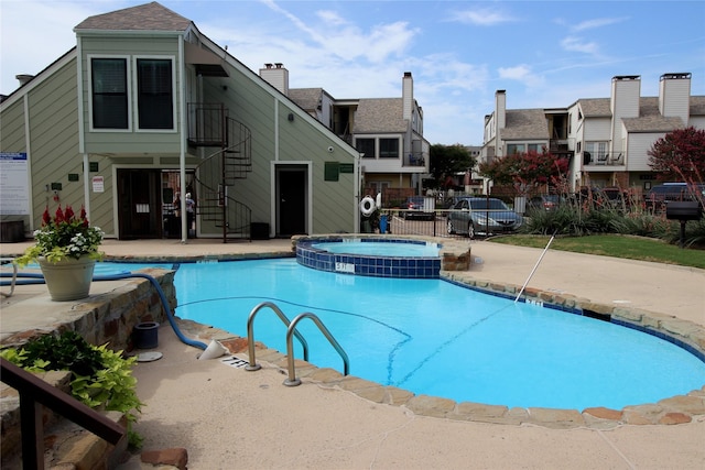 view of swimming pool featuring a patio, stairway, a pool with connected hot tub, and fence