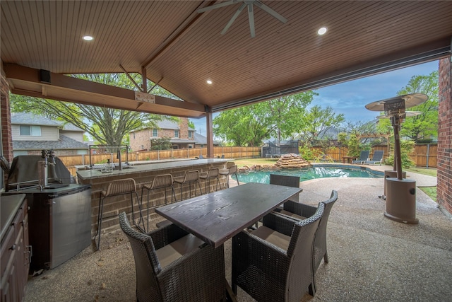 2325 Heather Ridge Dr, Flower Mound, TX 75028 - view of patio with outdoor wet bar, a fenced backyard, exterior kitchen, outdoor dining space, and a fenced in pool