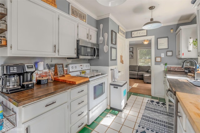 kitchen with crown molding, stainless steel microwave, wood counters, electric range, and light tile patterned flooring