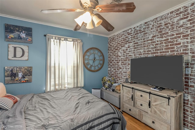 bedroom with brick wall, light wood-style floors, ornamental molding, and ceiling fan