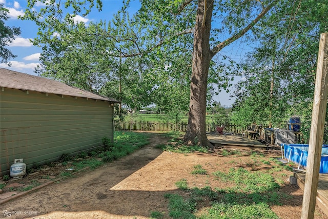 view of yard with a pool, a wooden deck, and fence