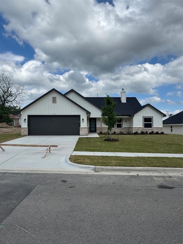 modern inspired farmhouse featuring board and batten siding, a chimney, a front lawn, concrete driveway, and an attached garage