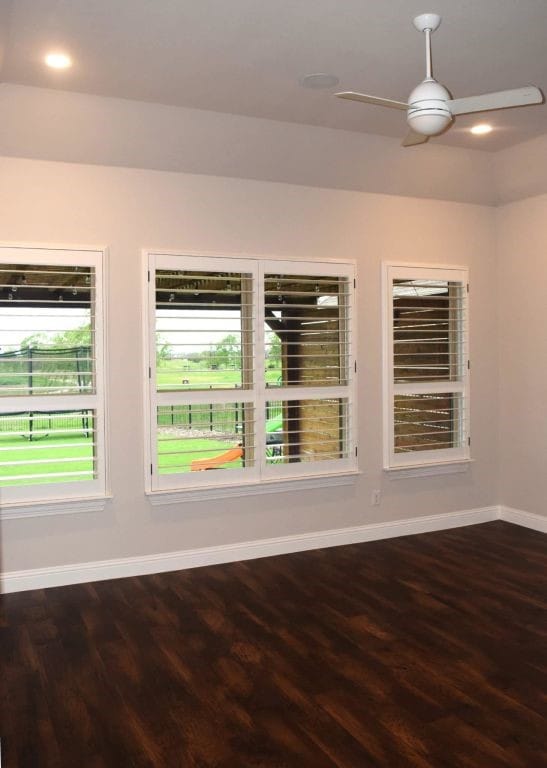 spare room featuring wood finished floors, ceiling fan, and baseboards