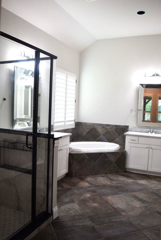 full bath featuring vanity, a garden tub, lofted ceiling, and a healthy amount of sunlight