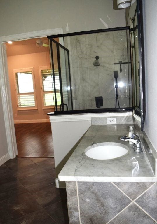 bathroom with tile patterned floors, baseboards, a shower stall, and vanity