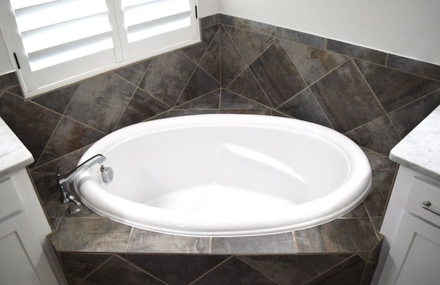bathroom featuring vanity, tile walls, and tiled bath