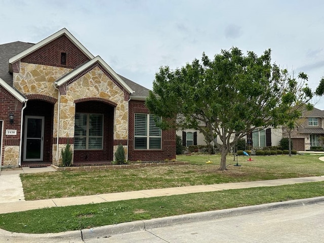 view of front facade featuring a front yard, brick siding, and stone siding