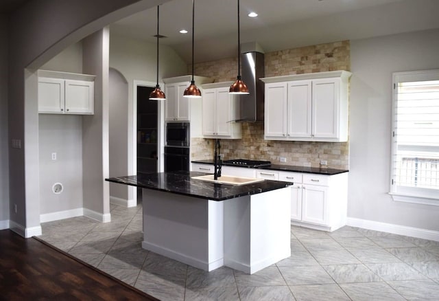kitchen with wall chimney range hood, white cabinetry, decorative backsplash, arched walkways, and black cooktop