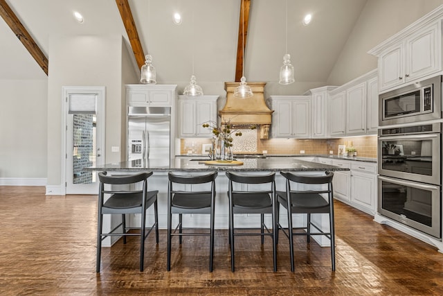 kitchen with white cabinetry, built in appliances, backsplash, and a kitchen island