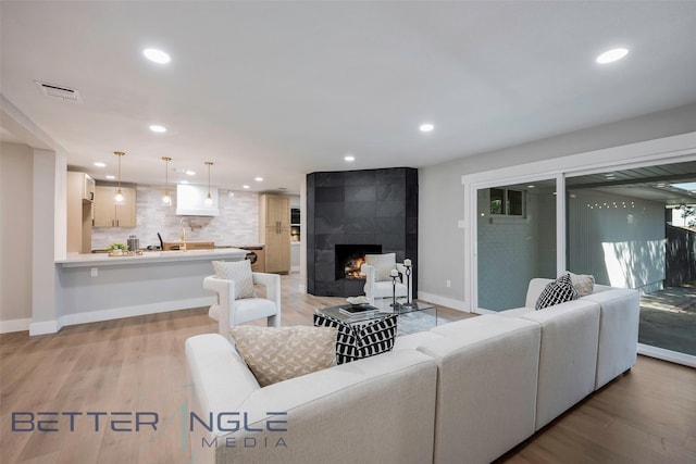 11006 Ferndale Rd, Dallas, TX 75238 - living room with light wood-type flooring, visible vents, recessed lighting, a tiled fireplace, and baseboards