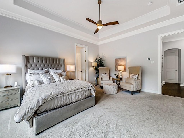 carpeted bedroom with baseboards, a ceiling fan, ornamental molding, and a raised ceiling