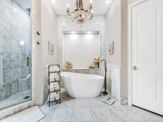 full bathroom with a freestanding tub, marble finish floor, a stall shower, and an inviting chandelier