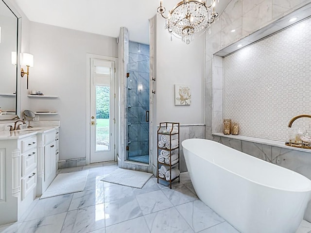 full bath with a freestanding bath, a notable chandelier, marble finish floor, a shower stall, and vanity