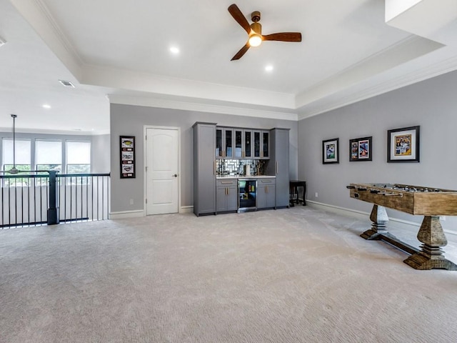 playroom featuring a bar, ornamental molding, beverage cooler, and a tray ceiling
