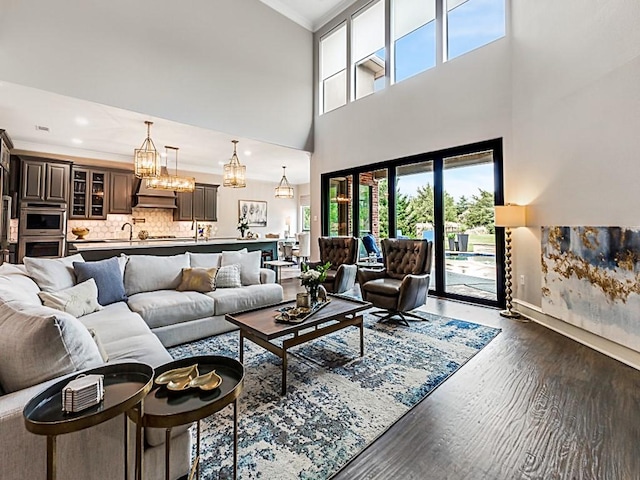 living room with crown molding, baseboards, dark wood-style floors, and a healthy amount of sunlight