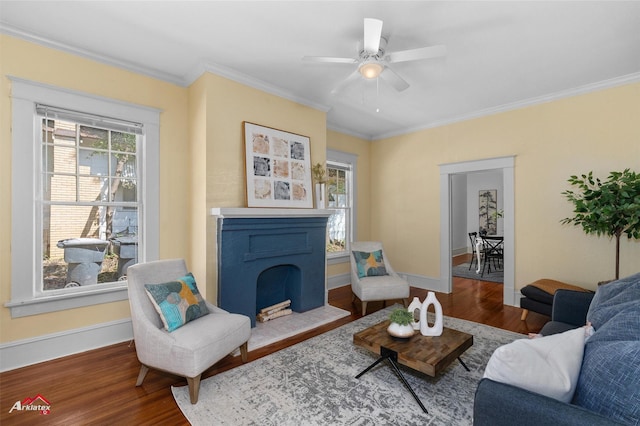 living area with crown molding, baseboards, wood finished floors, and a fireplace with flush hearth