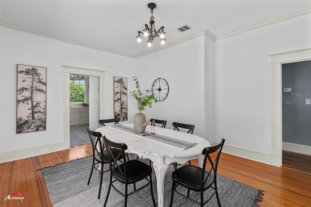 dining area with visible vents, baseboards, a chandelier, crown molding, and wood-type flooring