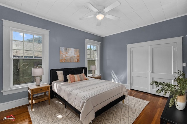bedroom with a ceiling fan, wood finished floors, baseboards, and ornamental molding