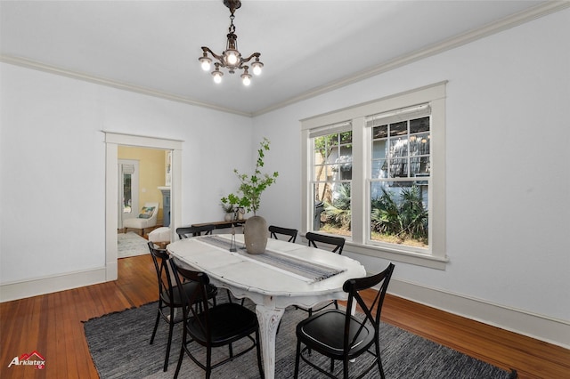 dining room featuring crown molding, an inviting chandelier, baseboards, and hardwood / wood-style flooring