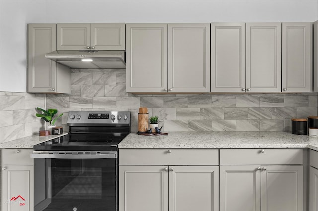 kitchen with under cabinet range hood, gray cabinetry, stainless steel range with electric cooktop, decorative backsplash, and light stone counters