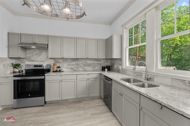 kitchen with ornamental molding, appliances with stainless steel finishes, under cabinet range hood, a sink, and gray cabinetry