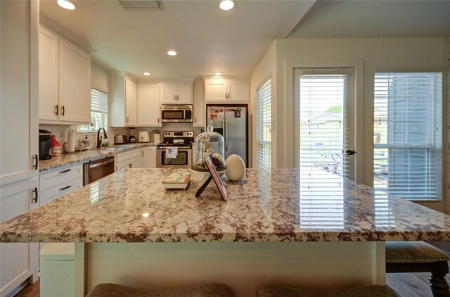 2109 Windy Dr, Garland, TX 75044 - kitchen with a sink, white cabinets, appliances with stainless steel finishes, and a breakfast bar area