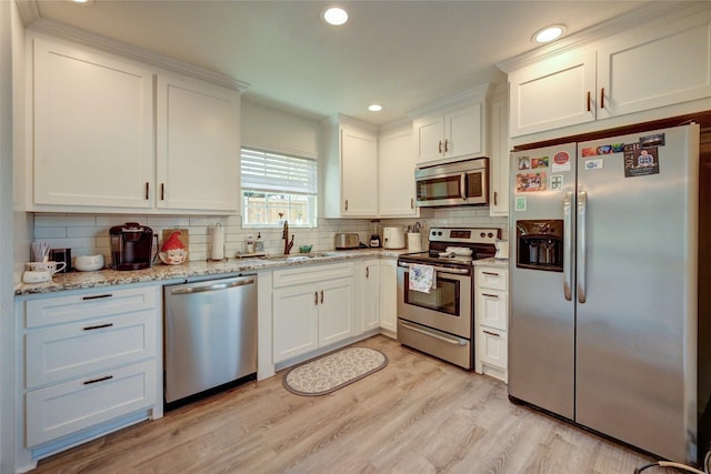 2109 Windy Dr, Garland, TX 75044 - kitchen with tasteful backsplash, white cabinetry, stainless steel appliances, light wood finished floors, and a sink