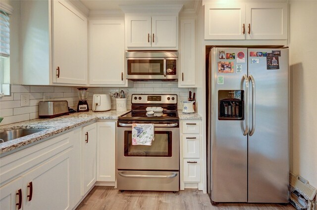 2109 Windy Dr, Garland, TX 75044 - kitchen with light wood-style floors, light stone countertops, white cabinets, appliances with stainless steel finishes, and decorative backsplash