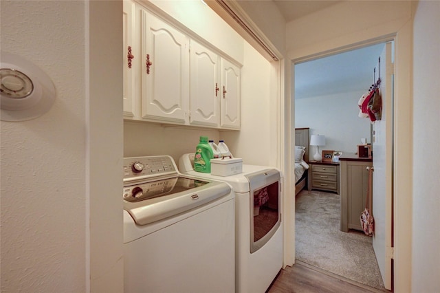 2109 Windy Dr, Garland, TX 75044 - clothes washing area with light wood-style floors, washing machine and dryer, and cabinet space
