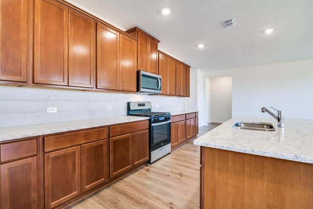 4031 Bedford Dr, Crandall, TX 75114 - kitchen with light wood finished floors, stainless steel appliances, a sink, visible vents, and brown cabinets
