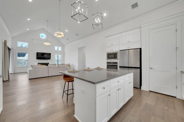 4729 Brockwell Dr, Carrollton, TX 75010 - kitchen with white cabinets, a kitchen island, visible vents, stainless steel appliances, and light wood finished floors