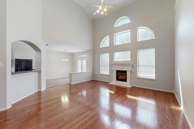 104 Bayonne Dr, Mansfield, TX 76063 - unfurnished living room featuring ceiling fan, wood finished floors, a fireplace with raised hearth, crown molding, and high vaulted ceiling