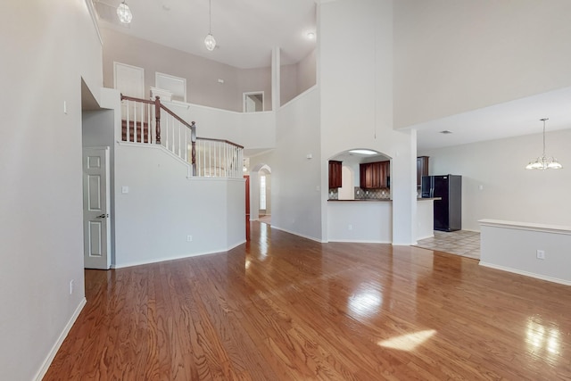 104 Bayonne Dr, Mansfield, TX 76063 - unfurnished living room featuring wood finished floors, a high ceiling, arched walkways, baseboards, and a chandelier