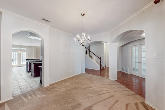 104 Bayonne Dr, Mansfield, TX 76063 - unfurnished dining area featuring french doors, arched walkways, light colored carpet, a chandelier, and ornamental molding