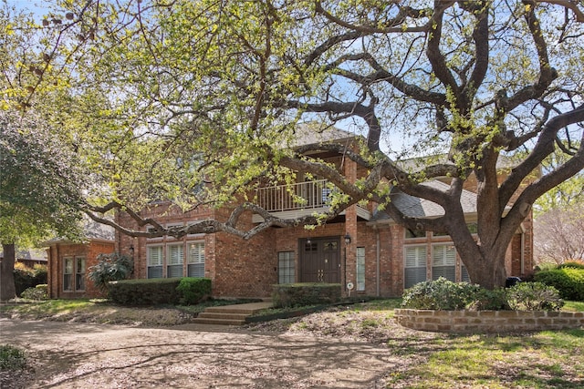 view of front of house with brick siding and a balcony