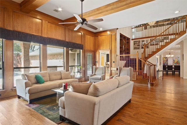 living room with visible vents, ceiling fan with notable chandelier, wood finished floors, and stairs