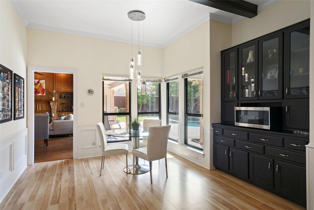 dining space featuring a decorative wall, ornamental molding, and light wood-type flooring
