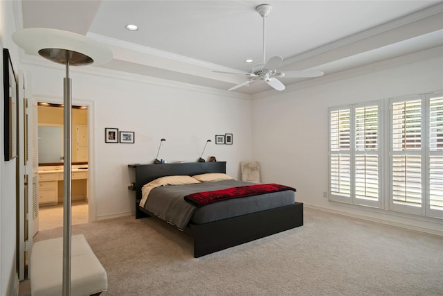 carpeted bedroom with ensuite bathroom, baseboards, ornamental molding, a tray ceiling, and recessed lighting