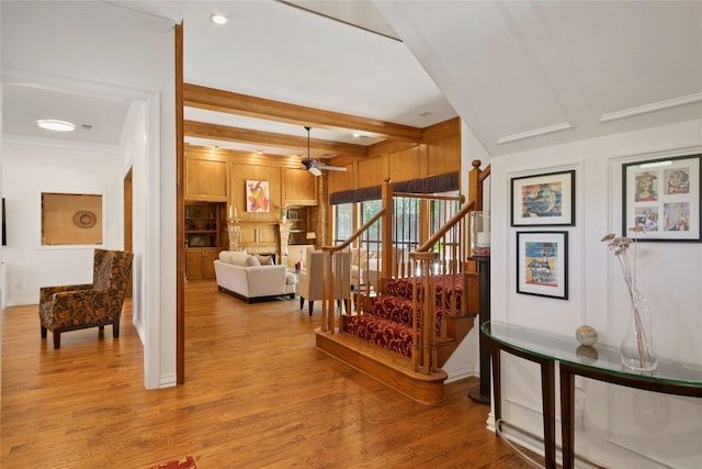 hall with light wood-style flooring, crown molding, beamed ceiling, and stairs
