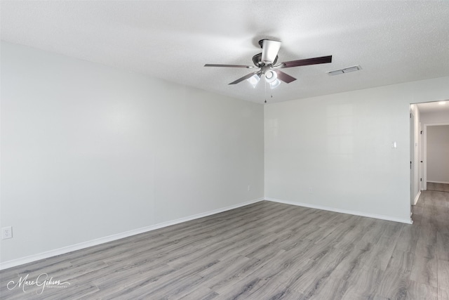 empty room featuring ceiling fan, baseboards, visible vents, and light wood-type flooring