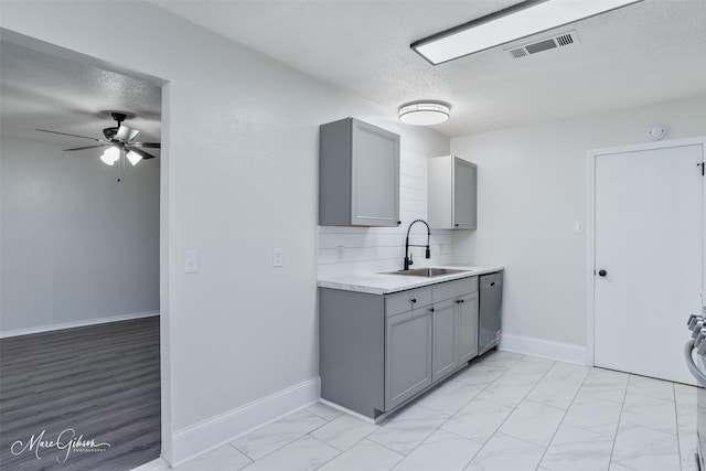 kitchen with a textured ceiling, a sink, and gray cabinetry