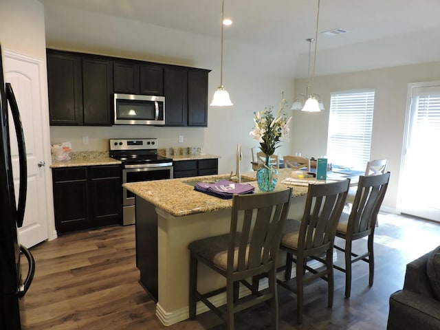 112 Westview Dr, Gun Barrel City, TX 75156 - kitchen featuring stainless steel appliances, a kitchen bar, light stone countertops, an island with sink, and decorative light fixtures