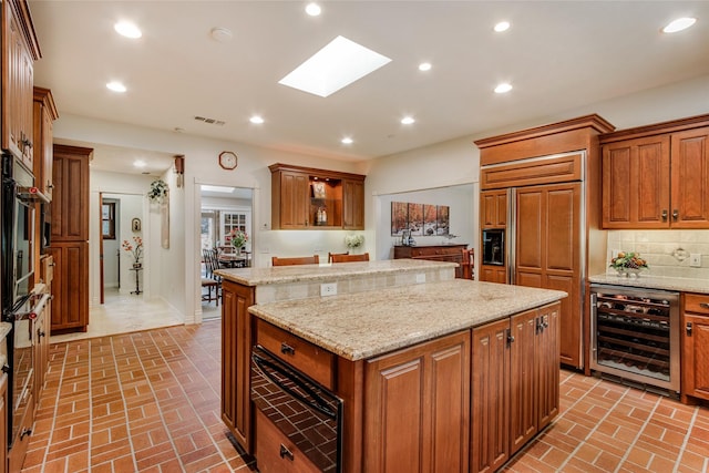 625 Estates Dr, Copper Canyon, TX 75077 - kitchen with wine cooler, brick patterned flooring, a kitchen island, a warming drawer, and a skylight